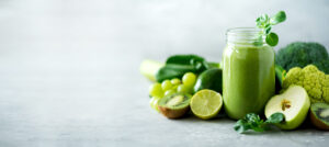 Glass jar mugs with green health smoothie, kale leaves, lime, apple, kiwi, grapes, banana, avocado, lettuce. Copy space. Raw, vegan, vegetarian, alkaline food concept. Banner.
